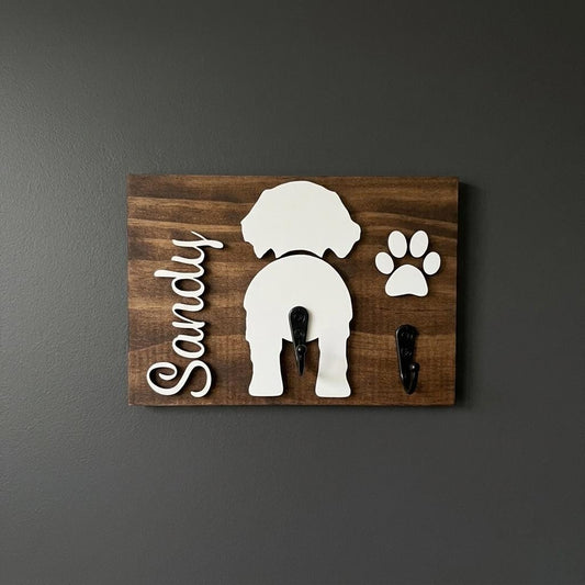 Personalized wooden dog butt leash holder with dog names and raised dog silhouettes above single hooks for leashes