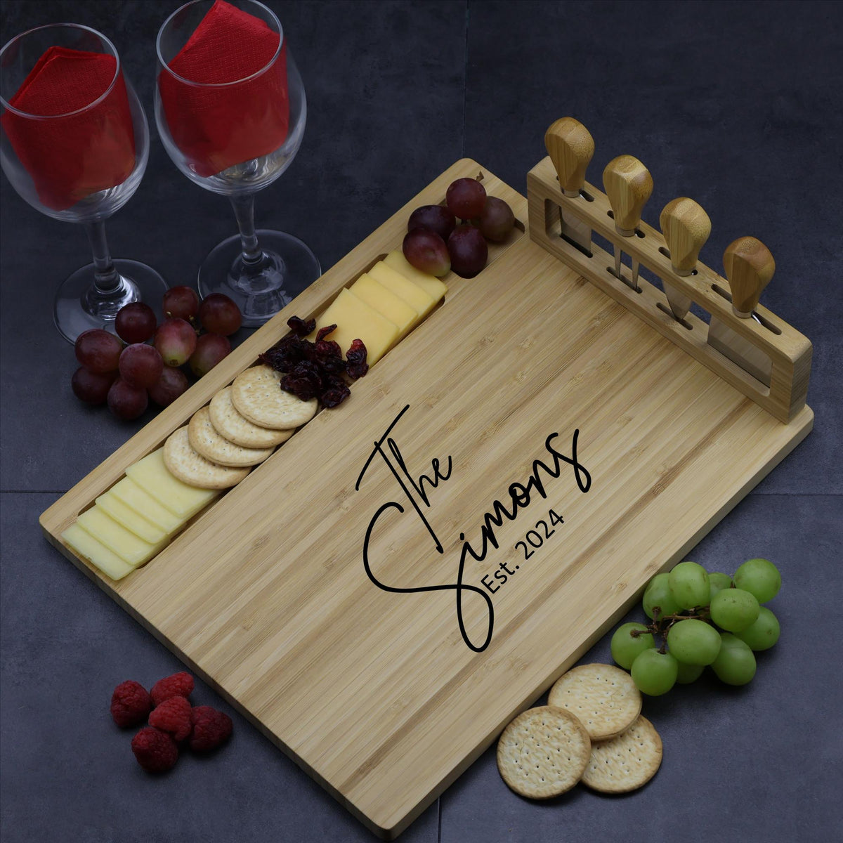 Personalized bamboo cheese board with custom engraving and a set of four cheese knives in the built-in holder