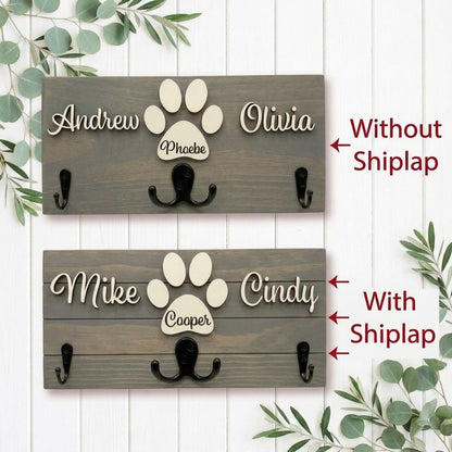 Personalized dog leash holder for wall with raised 3D names, engraved paw and black metal hooks on a stained pine board